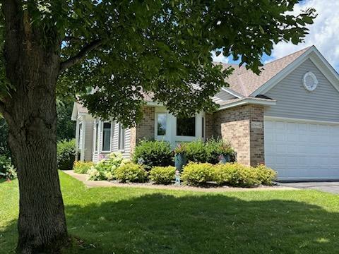 12440 Eagle Cir NW, Coon Rapids, MN 55448 - view of property hidden behind natural elements with a garage, brick siding, a front lawn, and driveway
