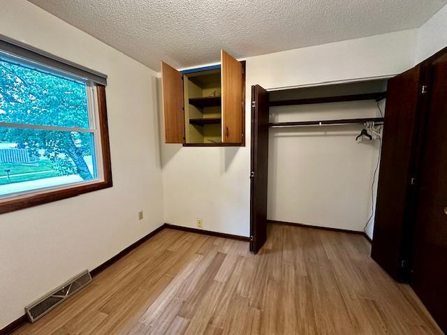 2671 4th Ave NE, Rochester, MN 55906 - unfurnished bedroom with light wood-style flooring, a closet, and a textured ceiling