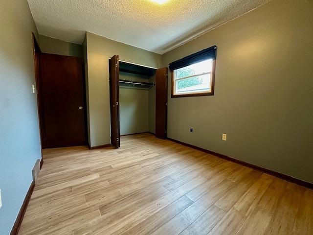 2671 4th Ave NE, Rochester, MN 55906 - unfurnished bedroom with light wood-style floors, a textured ceiling, and a closet