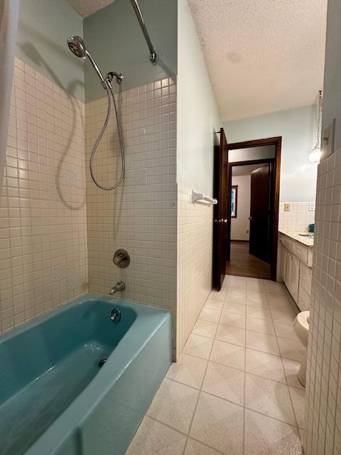 2671 4th Ave NE, Rochester, MN 55906 - full bathroom with tile walls, tile patterned floors, a textured ceiling, shower / bath combination, and vanity