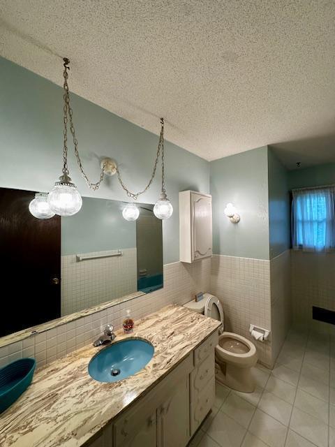 2671 4th Ave NE, Rochester, MN 55906 - bathroom with tile walls, tile patterned flooring, a wainscoted wall, vanity, and a textured ceiling