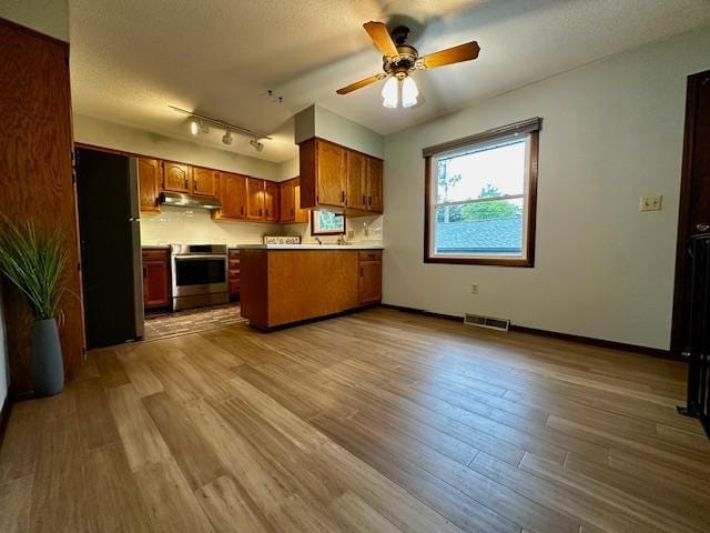2671 4th Ave NE, Rochester, MN 55906 - kitchen featuring range, under cabinet range hood, a peninsula, brown cabinetry, and ceiling fan