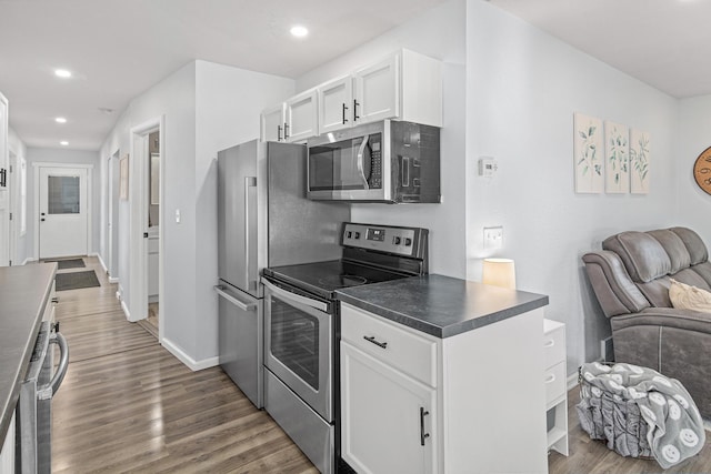 706 2nd Ave NW, New Brighton, MN 55112 - kitchen featuring appliances with stainless steel finishes, open floor plan, dark countertops, wood finished floors, and white cabinets