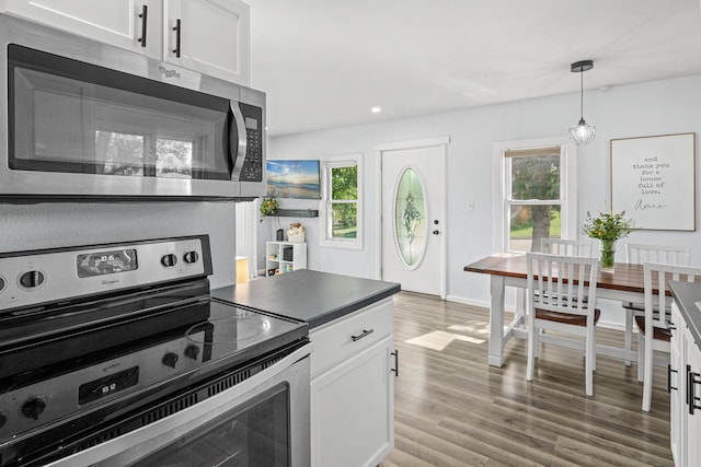 706 2nd Ave NW, New Brighton, MN 55112 - kitchen featuring stainless steel appliances, light wood-style floors, white cabinets, hanging light fixtures, and dark countertops