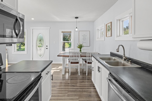 706 2nd Ave NW, New Brighton, MN 55112 - kitchen featuring stainless steel appliances, dark countertops, wood finished floors, white cabinetry, and decorative light fixtures