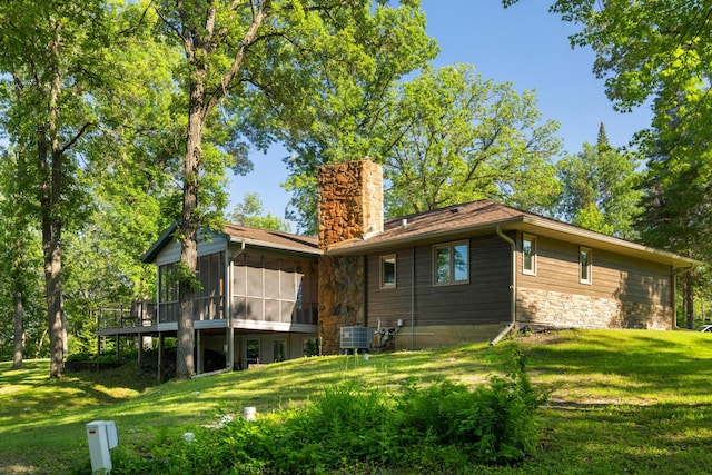 11100 Fisher Ln, Park Rapids, MN 56470 - rear view of house with a sunroom, a chimney, a yard, and stone siding