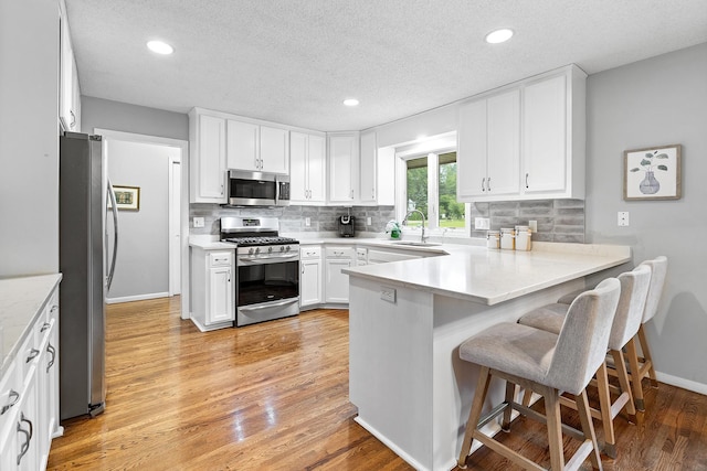 6721 Limerick Ln, Edina, MN 55439 - kitchen featuring stainless steel appliances, a peninsula, backsplash, white cabinetry, and a textured ceiling