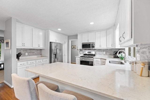 6721 Limerick Ln, Edina, MN 55439 - kitchen with stainless steel appliances, a peninsula, light stone counters, tasteful backsplash, and white cabinetry