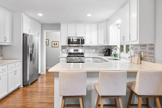 6721 Limerick Ln, Edina, MN 55439 - kitchen featuring stainless steel appliances, white cabinetry, a peninsula, light countertops, and recessed lighting