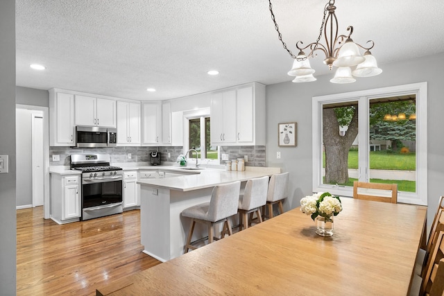 6721 Limerick Ln, Edina, MN 55439 - kitchen with appliances with stainless steel finishes, backsplash, white cabinets, light countertops, and a peninsula