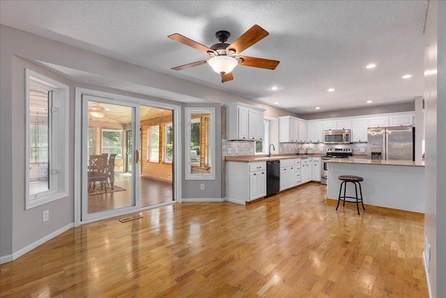 N6386 1317th St, Clifton Twp, WI 54021 - kitchen with appliances with stainless steel finishes, a breakfast bar, white cabinetry, backsplash, and recessed lighting