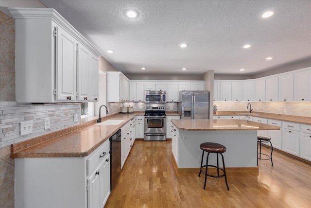 N6386 1317th St, Clifton Twp, WI 54021 - kitchen featuring stainless steel appliances, decorative backsplash, a kitchen bar, a center island, and a textured ceiling