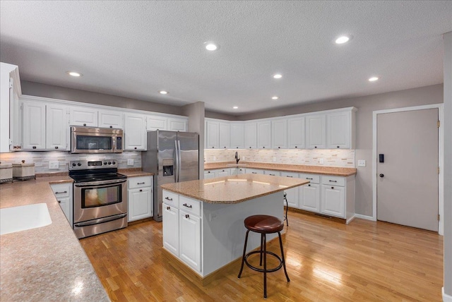 N6386 1317th St, Clifton Twp, WI 54021 - kitchen featuring appliances with stainless steel finishes, decorative backsplash, a kitchen island, white cabinets, and a breakfast bar