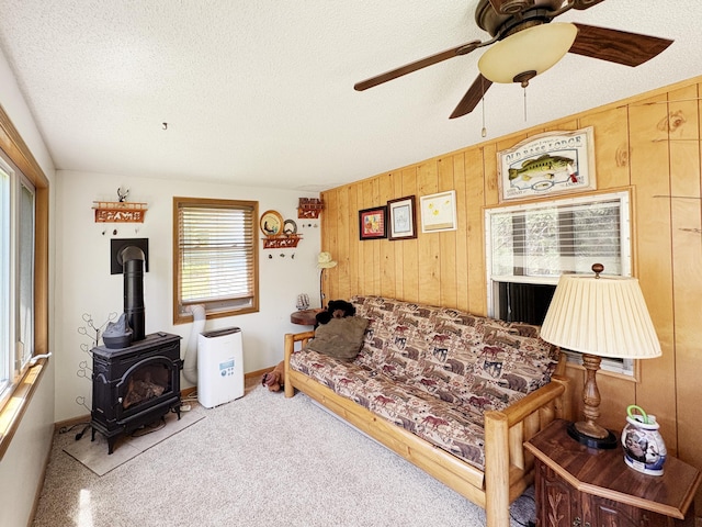 2890 216th St, Laketown Twp, WI 54853 - living room featuring a ceiling fan, a wood stove, wood walls, and a textured ceiling