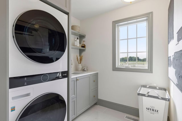 956 Mississippi River Blvd S, Saint Paul, MN 55116 - laundry area featuring stacked washer / drying machine, cabinet space, and light tile patterned floors
