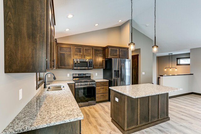 893 Grant St, Ellsworth, WI 54011 - kitchen with appliances with stainless steel finishes, a kitchen island, dark brown cabinetry, light wood-style floors, and decorative light fixtures