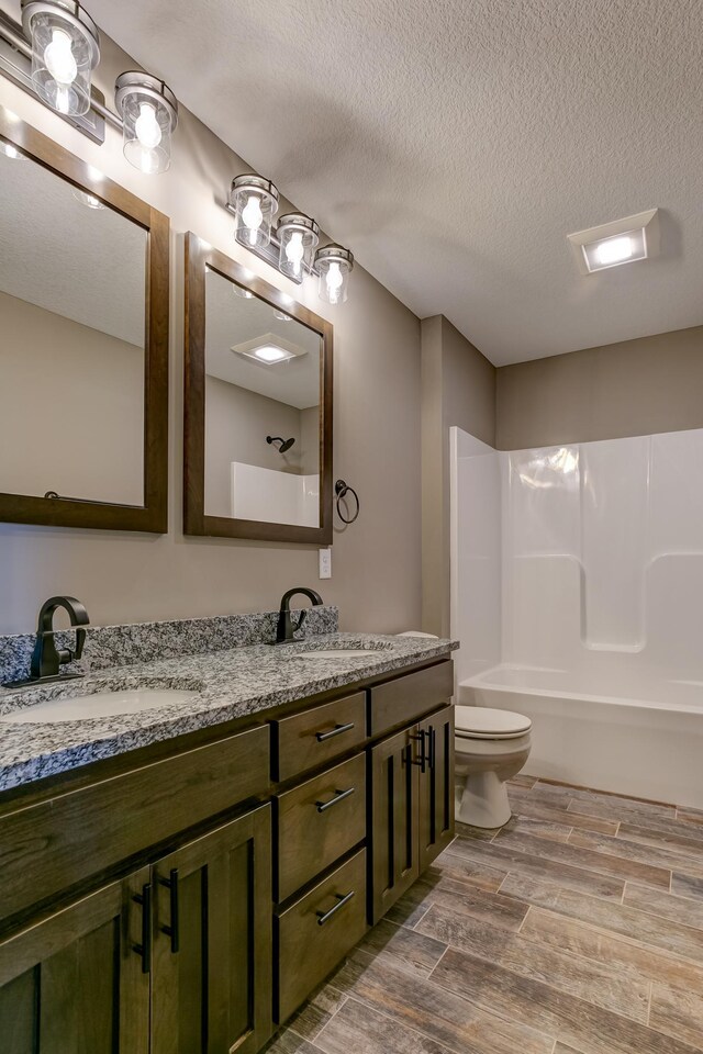 893 Grant St, Ellsworth, WI 54011 - bathroom featuring wood tiled floors, double vanity, and a textured ceiling