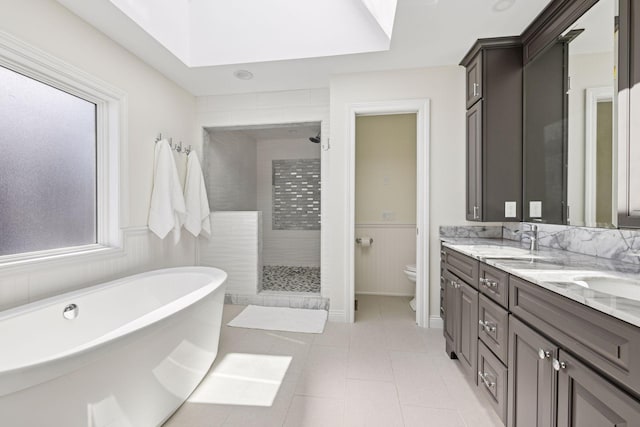 2807 Mckenzie Point Rd, Minnetonka, MN 55391 - bathroom featuring a tile shower, double vanity, a freestanding bath, a wainscoted wall, and a skylight