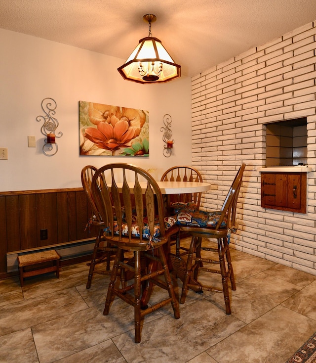 22761 105th Ave, Milaca, MN 56353 - dining area featuring brick wall, a textured ceiling, wooden walls, and wainscoting