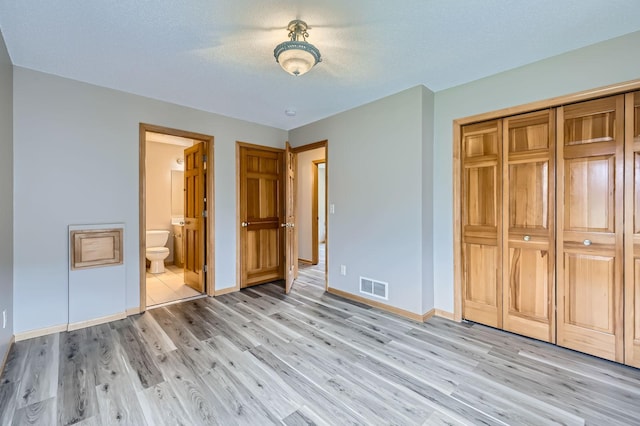12740 Eveleth Path, Apple Valley, MN 55124 - unfurnished bedroom featuring light wood finished floors, a closet, a textured ceiling, and ensuite bathroom