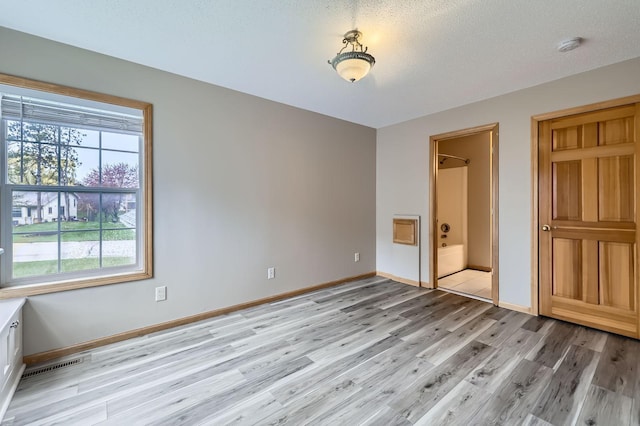 12740 Eveleth Path, Apple Valley, MN 55124 - unfurnished bedroom featuring light wood-type flooring, connected bathroom, and a textured ceiling