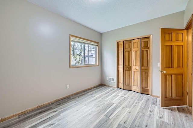 12740 Eveleth Path, Apple Valley, MN 55124 - unfurnished bedroom with light wood finished floors, a textured ceiling, and a closet