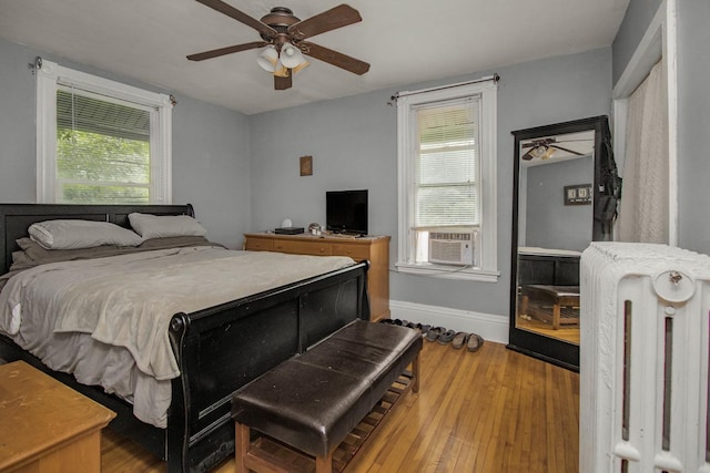 310 4th Ave SW, Hutchinson, MN 55350 - bedroom with radiator heating unit, multiple windows, wood finished floors, and a ceiling fan