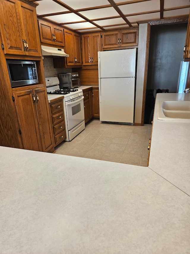 5306 Boulder Ln, Brooklyn Center, MN 55429 - kitchen featuring white appliances, under cabinet range hood, brown cabinets, light tile patterned floors, and light countertops