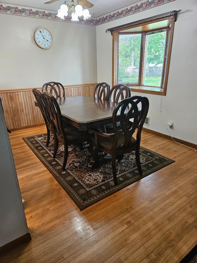 5306 Boulder Ln, Brooklyn Center, MN 55429 - dining area with wainscoting, light wood-style floors, wooden walls, and a ceiling fan