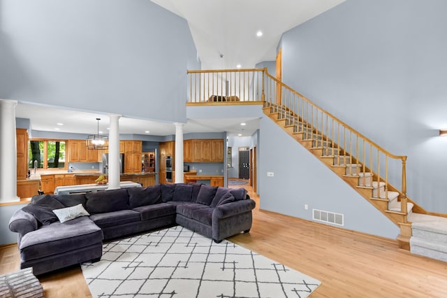 6354 Oxbow Bnd, Chanhassen, MN 55317 - living room with decorative columns, light wood finished floors, a high ceiling, stairway, and recessed lighting