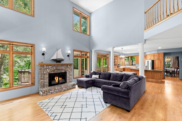 6354 Oxbow Bnd, Chanhassen, MN 55317 - living area with decorative columns, a high ceiling, healthy amount of natural light, light wood-style floors, and a fireplace