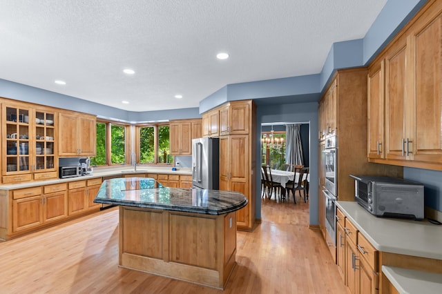 6354 Oxbow Bnd, Chanhassen, MN 55317 - kitchen featuring appliances with stainless steel finishes, a kitchen island, light wood-type flooring, healthy amount of natural light, and a textured ceiling