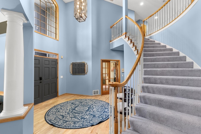 6354 Oxbow Bnd, Chanhassen, MN 55317 - foyer featuring a towering ceiling, ornate columns, stairs, wood finished floors, and a chandelier
