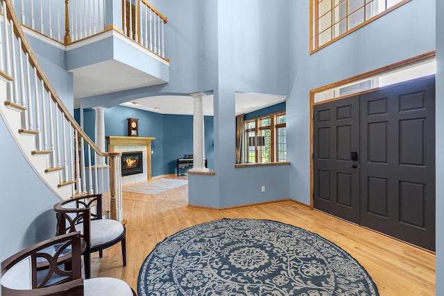 6354 Oxbow Bnd, Chanhassen, MN 55317 - entrance foyer with decorative columns, wood finished floors, a high ceiling, a tile fireplace, and stairway