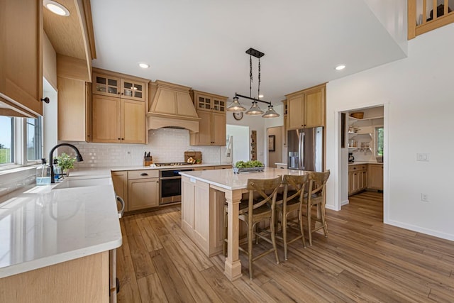 13827 Halstad Ave, Lonsdale, MN 55046 - kitchen with custom exhaust hood, stainless steel appliances, light wood-style floors, a breakfast bar, and backsplash