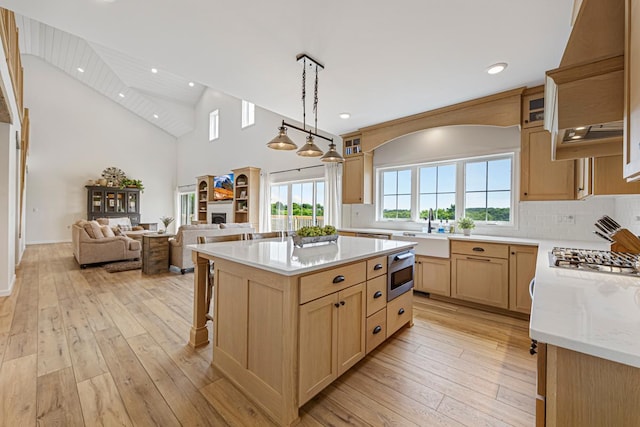 13827 Halstad Ave, Lonsdale, MN 55046 - kitchen featuring custom exhaust hood, light brown cabinets, stainless steel microwave, open floor plan, and light wood-style flooring