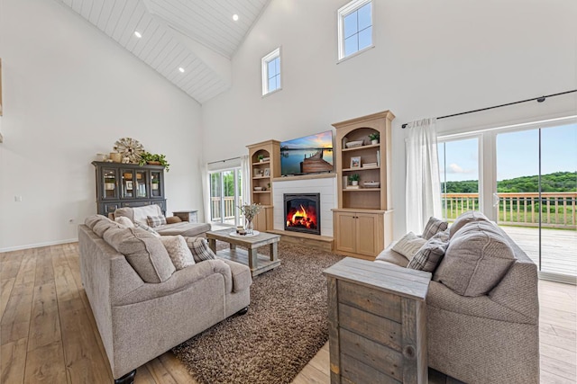 13827 Halstad Ave, Lonsdale, MN 55046 - living area featuring high vaulted ceiling, light wood-style floors, healthy amount of natural light, a glass covered fireplace, and recessed lighting