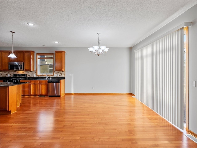 1788 Fescue Ct, Shakopee, MN 55379 - kitchen with stainless steel appliances, a textured ceiling, light wood finished floors, a chandelier, and tasteful backsplash