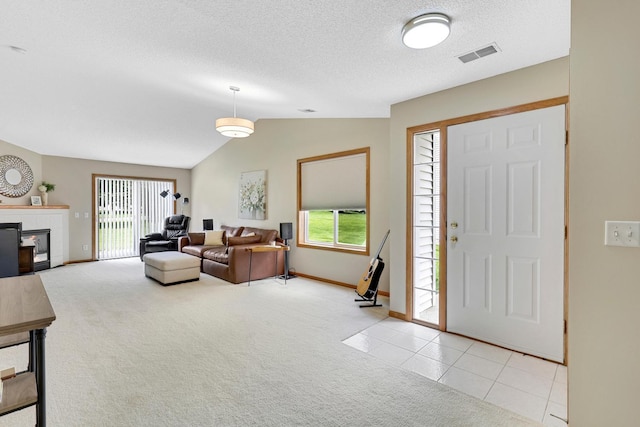 314 Archibald Ln, Dundas, MN 55019 - entryway featuring lofted ceiling, light colored carpet, a glass covered fireplace, a textured ceiling, and light tile patterned flooring