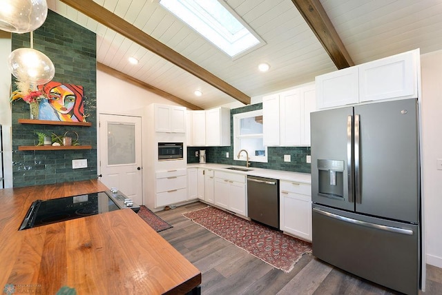 2833 1st St N, Fargo, ND 58102 - kitchen featuring appliances with stainless steel finishes, a skylight, dark wood-type flooring, white cabinetry, and tasteful backsplash