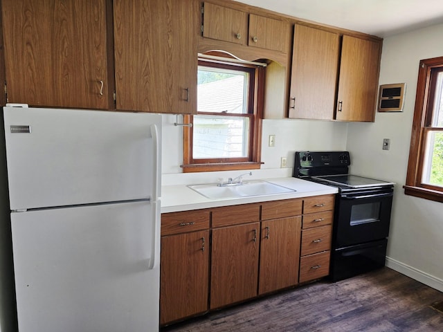 915 14th Ave SE, Austin, MN 55912 - kitchen with freestanding refrigerator, black electric range oven, dark wood finished floors, light countertops, and brown cabinetry