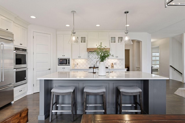 6333 Yuma Ln N, Maple Grove, MN 55311 - kitchen featuring built in appliances, decorative backsplash, a kitchen island with sink, glass insert cabinets, and light countertops