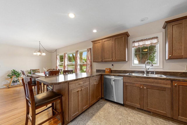 511 9th Ave SW, Faribault, MN 55021 - kitchen featuring dishwasher, a peninsula, a breakfast bar, dark countertops, and brown cabinetry