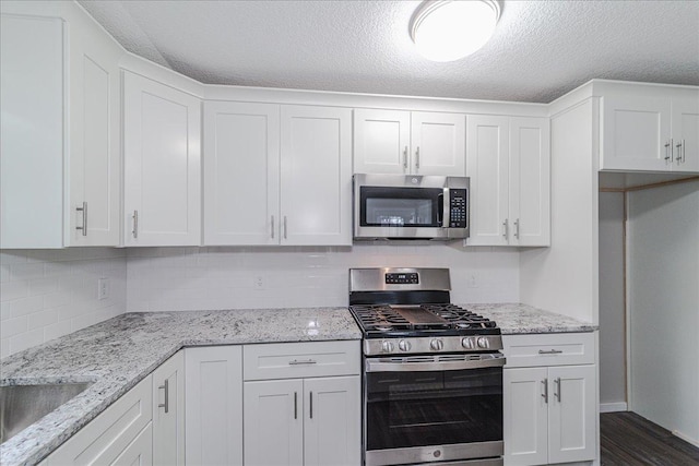 3667 205th St W, Farmington, MN 55024 - kitchen with stainless steel appliances, white cabinetry, a textured ceiling, tasteful backsplash, and light stone counters