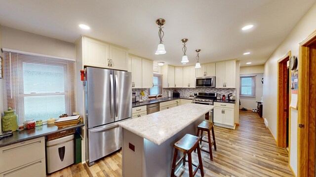 216 1st St, Kiester, MN 56051 - kitchen featuring appliances with stainless steel finishes, a kitchen breakfast bar, light wood finished floors, backsplash, and a center island