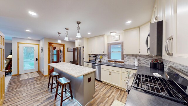 216 1st St, Kiester, MN 56051 - kitchen with stainless steel appliances, decorative backsplash, light wood finished floors, a kitchen bar, and a kitchen island