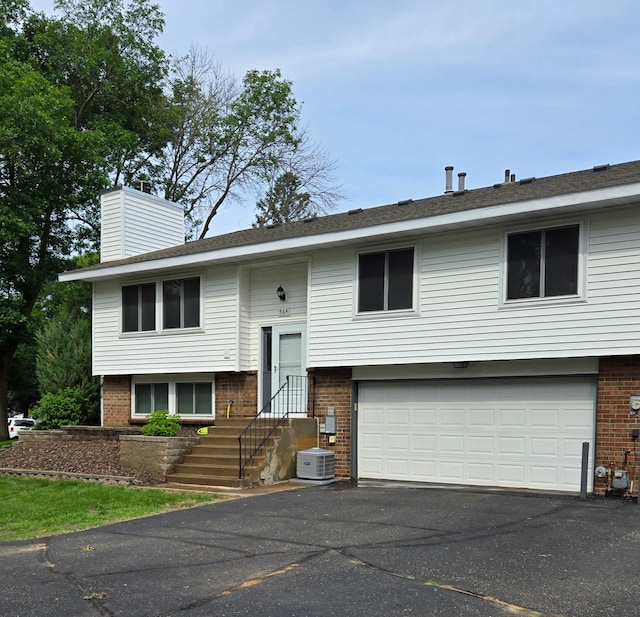 564 98th Ln NE, Blaine, MN 55434 - raised ranch with brick siding, an attached garage, driveway, and a chimney