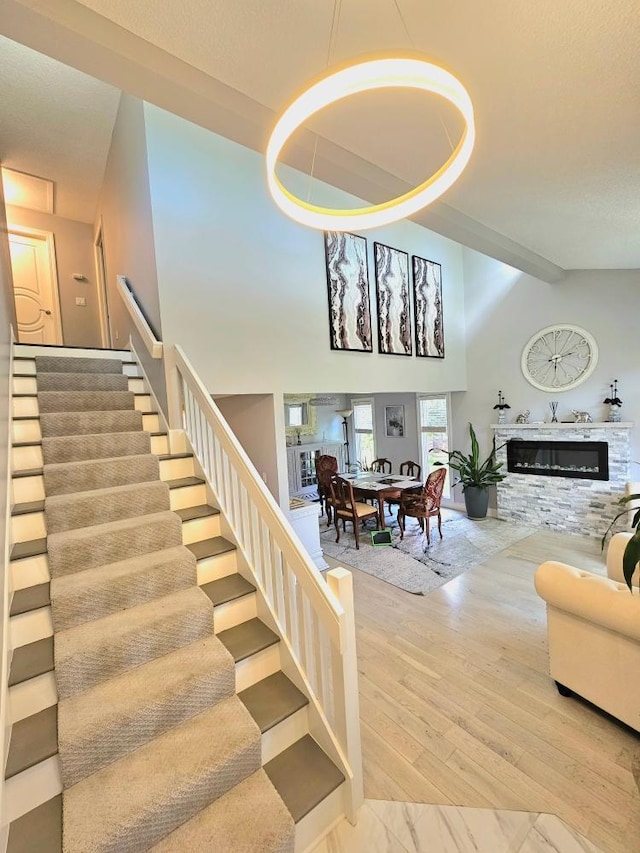 904 155th St, Burnsville, MN 55306 - stairway featuring wood finished floors, a glass covered fireplace, and high vaulted ceiling