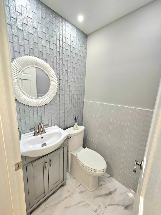 904 155th St, Burnsville, MN 55306 - half bath with vanity, marble finish floors, tile walls, and a wainscoted wall