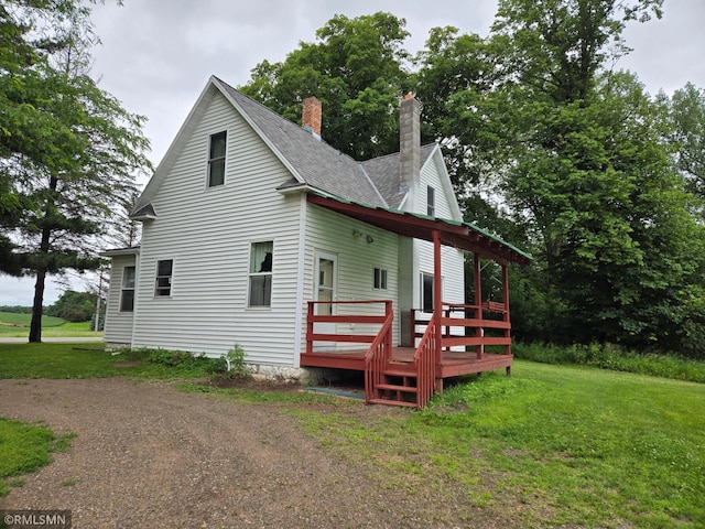 1264 389th Ave NE, Stanchfield Twp, MN 55080 - view of property exterior with a chimney, a wooden deck, a lawn, and a shingled roof